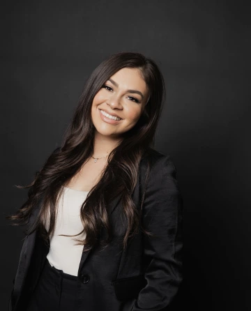 Picture of Anahi smiling in front of a black background